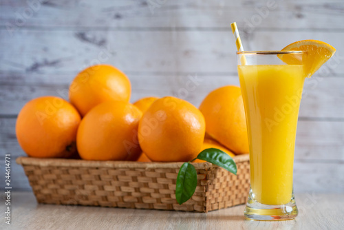 Glass of freshly squeezed orange juice standing on light background with a fresh oranges