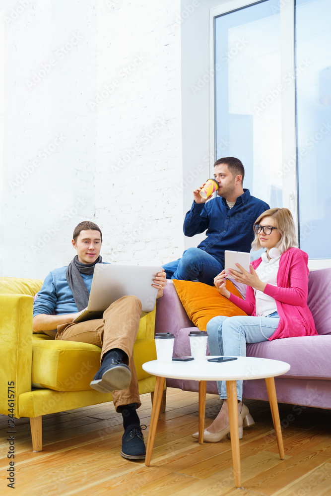 Friends sit on the couch, chatting and using a smartphone, desktop computer, laptop. Friends sit on the couch, chatting and using a smartphone, desktop computer, laptop.