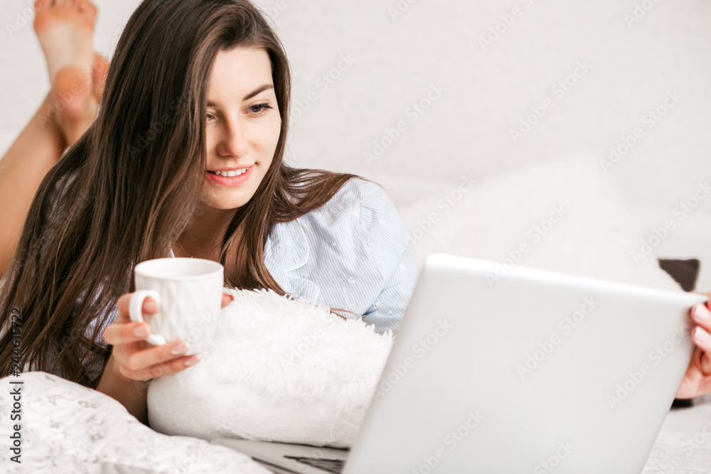 Young smiling woman working on laptop in her bedroom. Happy morning. Young smiling woman working on laptop in her bedroom. Happy morning.