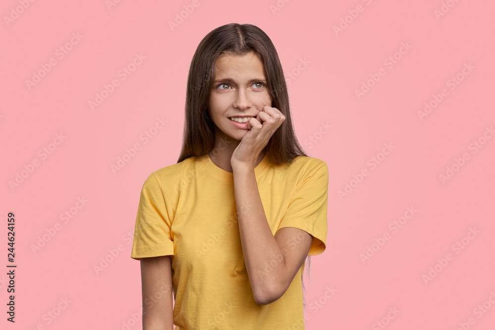 Fearful girl with frightened expression as notices large insect, trembles from fear, keeps hands near mouth. Isolated on pink background in Studio Fearful girl with frightened expression as notices large insect, trembles from fear, keeps hands near mouth. Isolated on pink background in Studio
