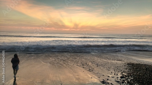 Silueta de mujer en la orilla del mar al atardecer