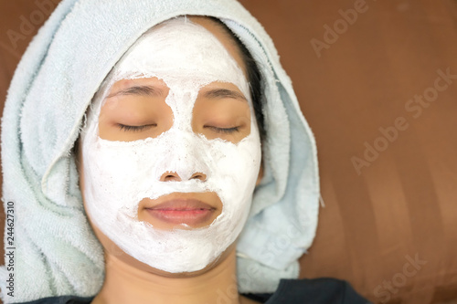 Asian girl applying facial cream mask.