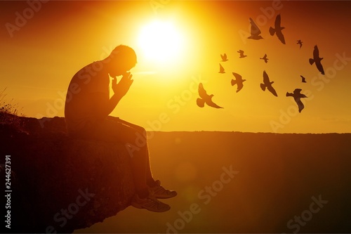 Young man pray outdoor on top of mountains in sunset photo