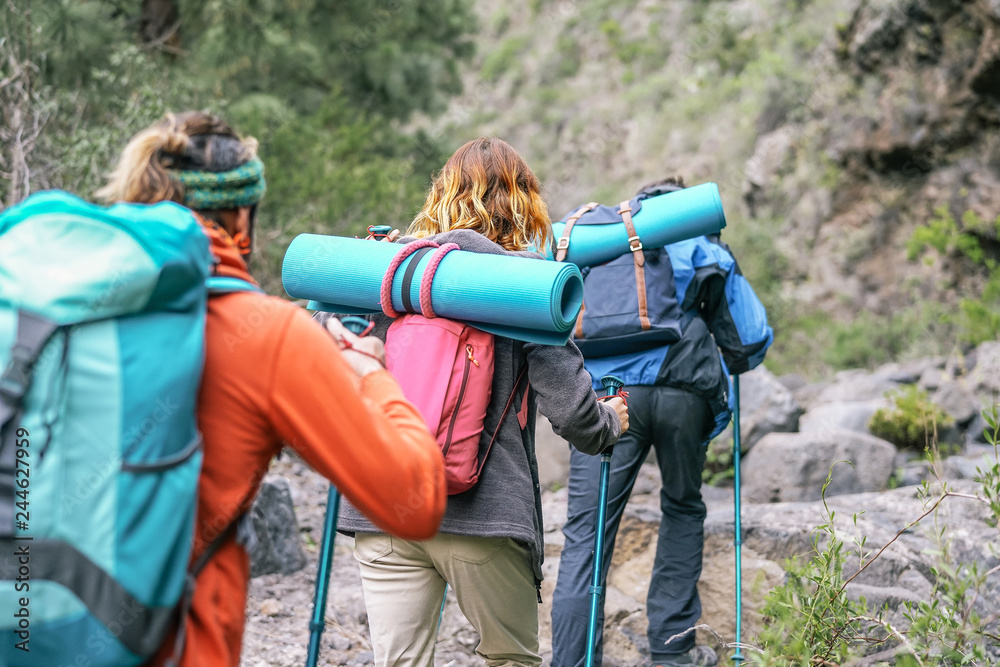 Group of people with backpacks doing trekking excursion on mountain - Young  tourists walking and exploring the nature - Trekker, hike and travel concept