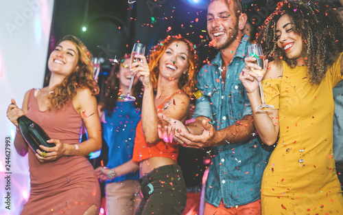 Happy friends doing party drinking champagne and dancing in the club - Millennials young people having fun celebrating in the nightclub - Nightlife, entertainment and festive holidays concept