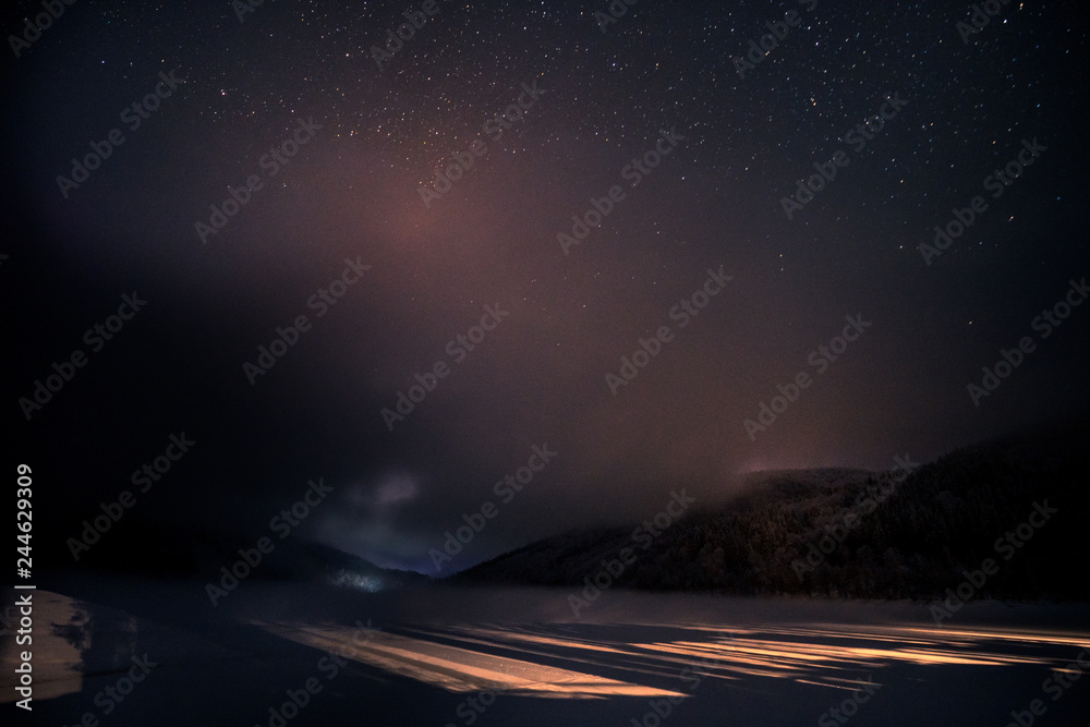 Puple night sky with the stars over the winter mountains with snow