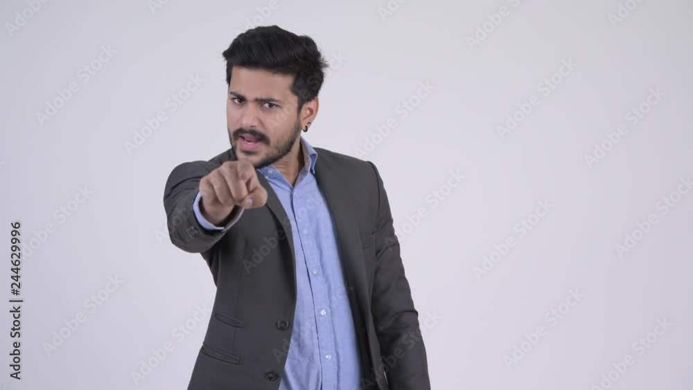 Young angry bearded Indian businessman talking and pointing at camera Young angry bearded Indian businessman talking and pointing at camera