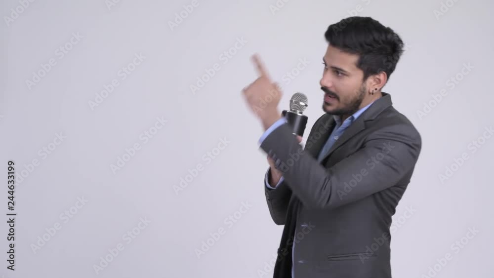 Young Indian businessman as newscaster presenting something Young Indian businessman as newscaster presenting something