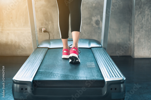 Sporty woman exercise running on treadmill machine in fitness gym., Close-up of runner shoes on track, Fitness and healthy lifestyle concept.