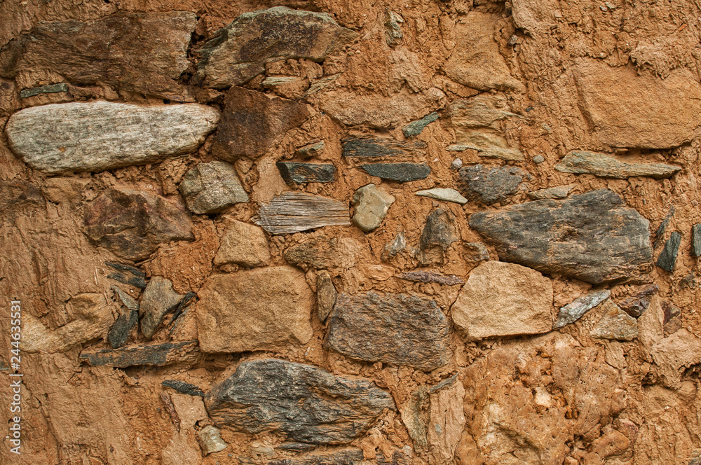 Old grunge weathered stone wall of rural farm house closeup as background