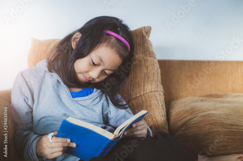 Happy a girl reading blue bible on sofa at home. young christian concept. photo