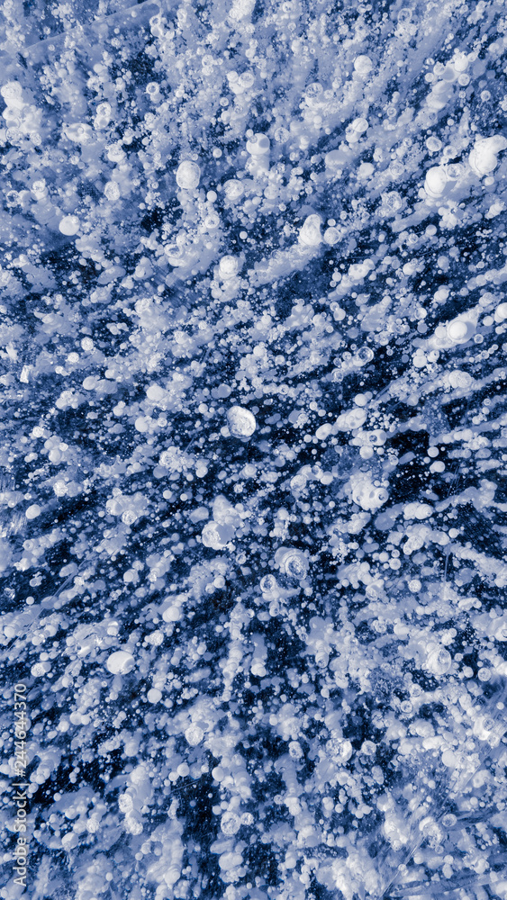 Fototapeta premium The frozen lake surface, showing a variety of textures. Blue background of Ice texture. 