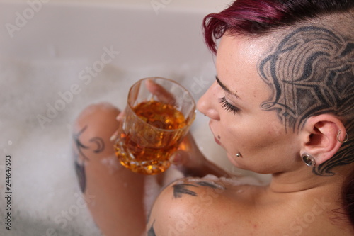 Glamour young woman bathing and relaxing with a glass of whiskey in her hands