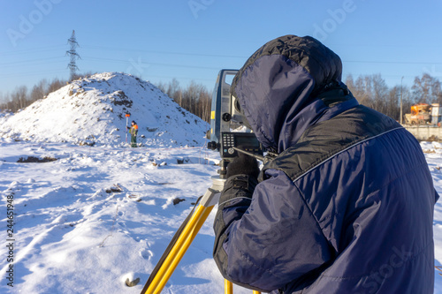 Surveyor in the winter on the construction site conducts topographic and cadastral work