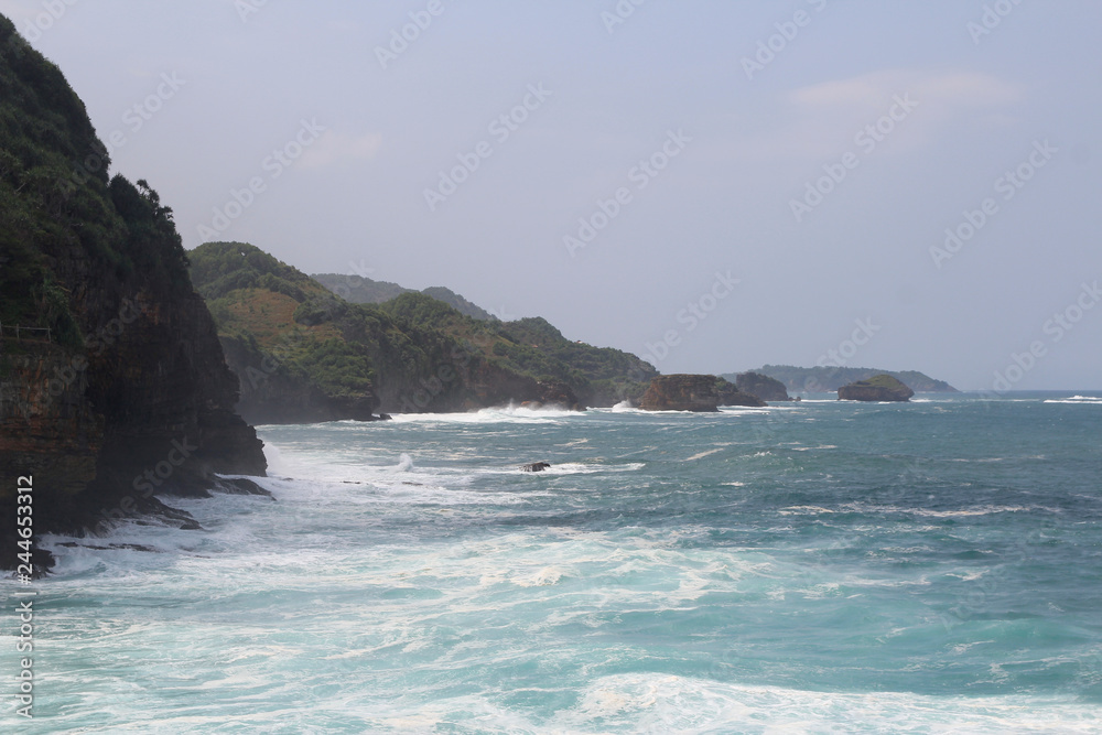 Natural cliff formation with the wave at Timang Beach in sunny day, Yogyakarta, Indonesiaa