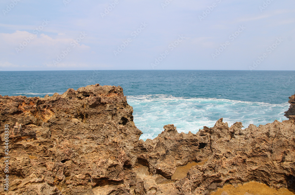 Natural rock formation with the wave at Timang Beach in sunny day, Yogyakarta, Indonesia