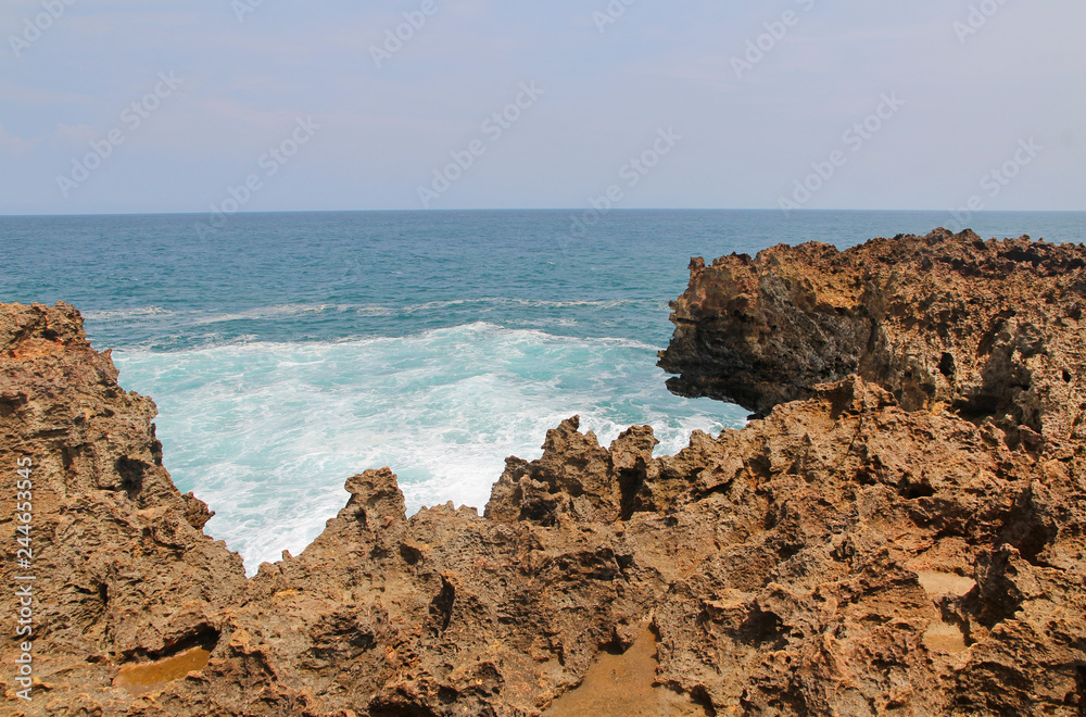 Natural rock formation with the wave at Timang Beach in sunny day, Yogyakarta, Indonesia