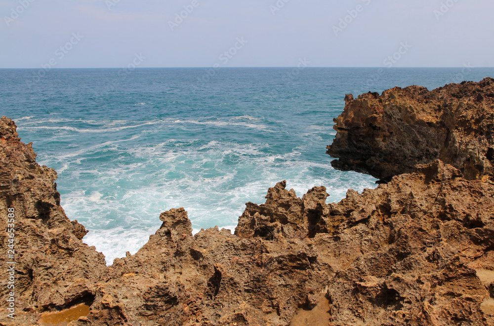 Natural rock formation with the wave at Timang Beach in sunny day, Yogyakarta, Indonesia