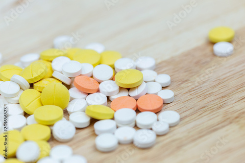 Colorful medicine pills tablets or drugs closeup on wood table background.