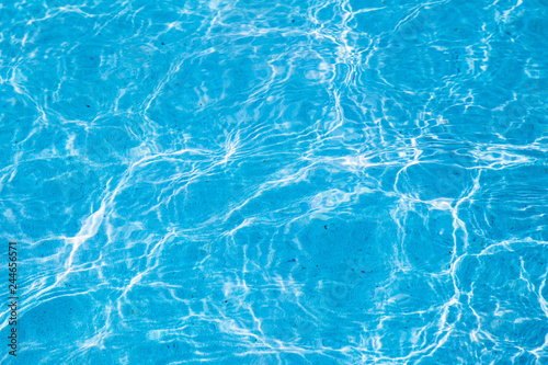 Blue ripped water in swimming pool with sunny reflections for background design.