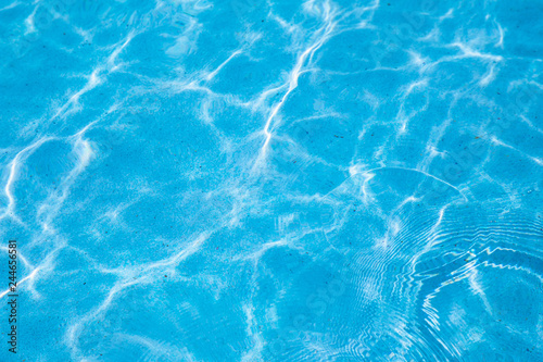Blue ripped water in swimming pool with sunny reflections for background design.