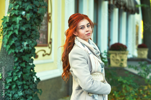 Young redheaded woman in town . Girl wearing a coat