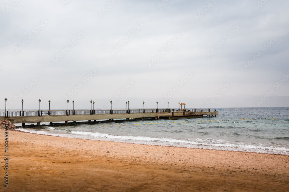 Beach, sea and pier in the water on a cloudy summer day