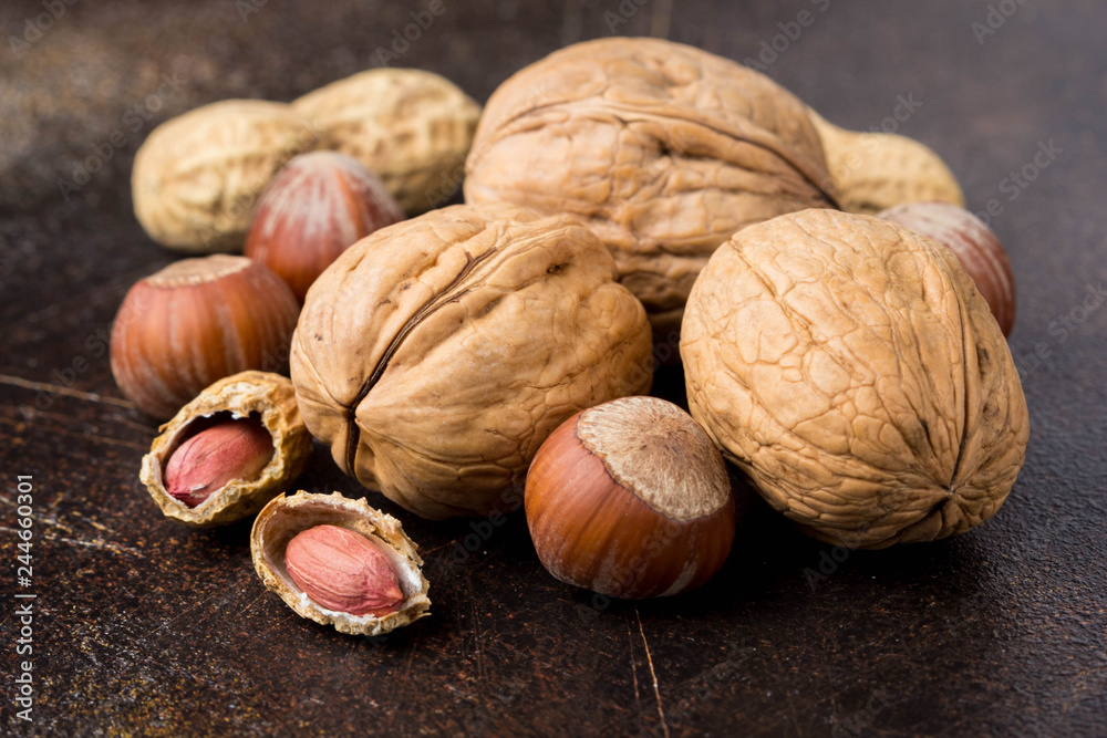 Bunch of nuts in shell and peeled on dark background. Walnuts, hazelnuts and peanuts. Tasty healthy snack, food