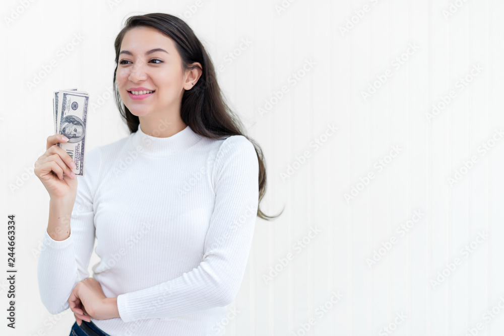 Attractive Asian woman hold bunch of dollars banknotes at office after success to invest in stock market with white wall background, money, cash, salary, investment and banking concept. Attractive Asian woman hold bunch of dollars banknotes at office after success to invest in stock market with white wall background, money, cash, salary, investment and banking concept.