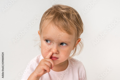 Baby girl is picking her nose with finger inside