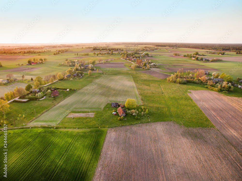 Obraz premium Aerial drone view of old farmhouses, barns, houses and trees during sunset. Calm, peaceful landscape of countryside. Concept of agriculture industry