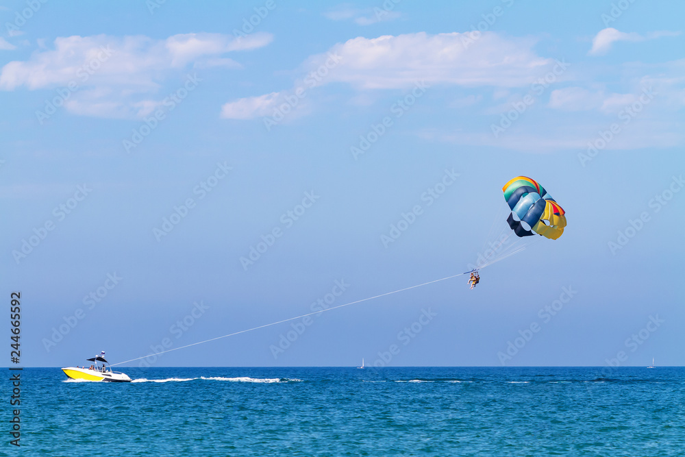 Parasailing water amusement - flying on a parachute behind a boat on a summer holiday by the sea in the resort Parasailing water amusement - flying on a parachute behind a boat on a summer holiday by the sea in the resort