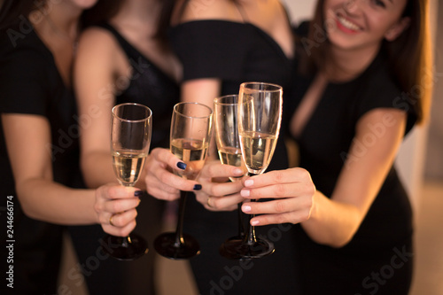 Cheers! Group of people cheering with champagne flutes with holiday lights on background with copy space.