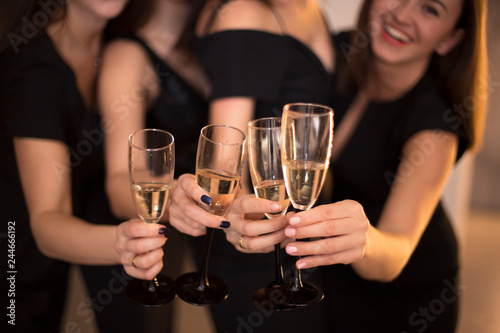 Cheers! Group of people cheering with champagne flutes with holiday lights on background with copy space.