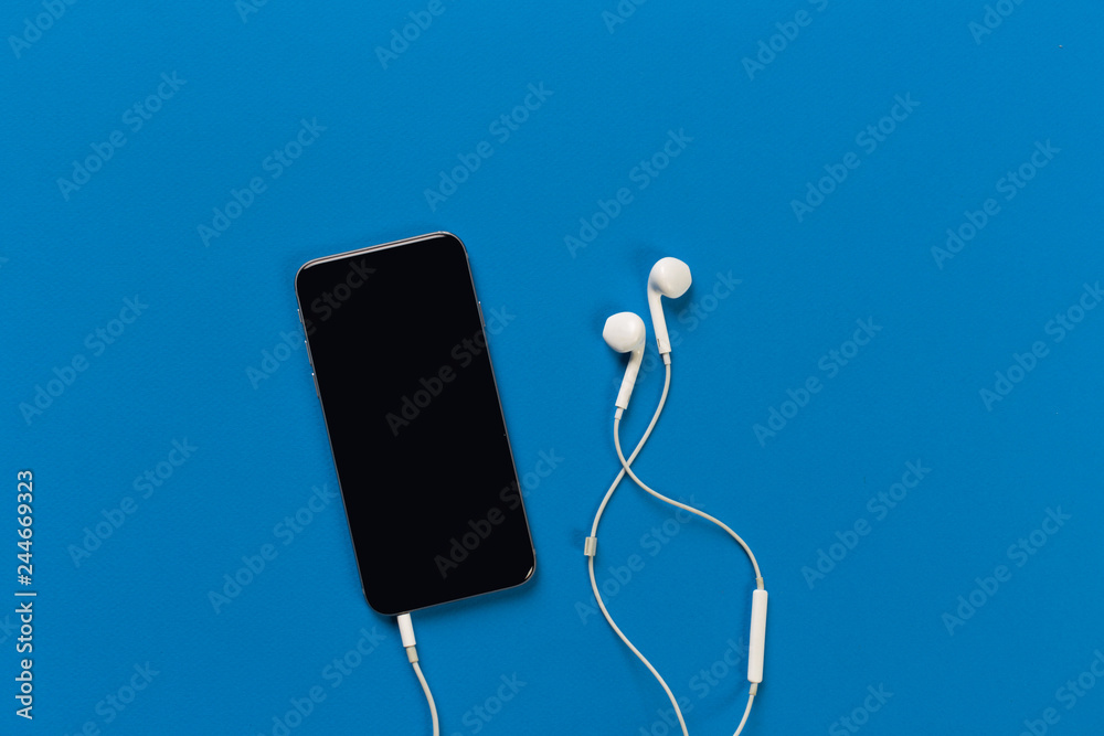 Mobile phone with white earphones on colour backgroung, top view Mobile phone with white earphones on colour backgroung, top view