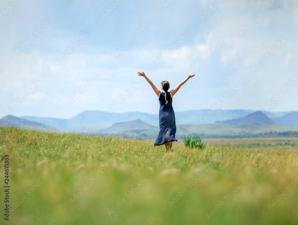 Happy woman stand and show hand in to sky, in field, against the backdrop of the mountains, subject is blurred Happy woman stand and show hand in to sky, in field, against the backdrop of the mountains, subject is blurred