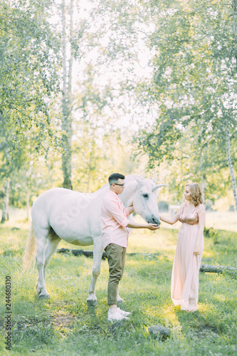 Fabulous photo shoot of a couple with a unicorn. Air series in the sunset in the forest with a horse.