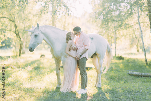 Fabulous photo shoot of a couple with a unicorn. Air series in the sunset in the forest with a horse.