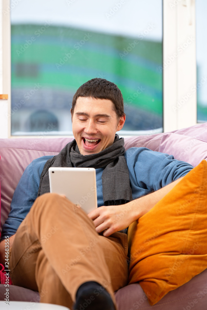 Man sit on the couch and using a tablet computer