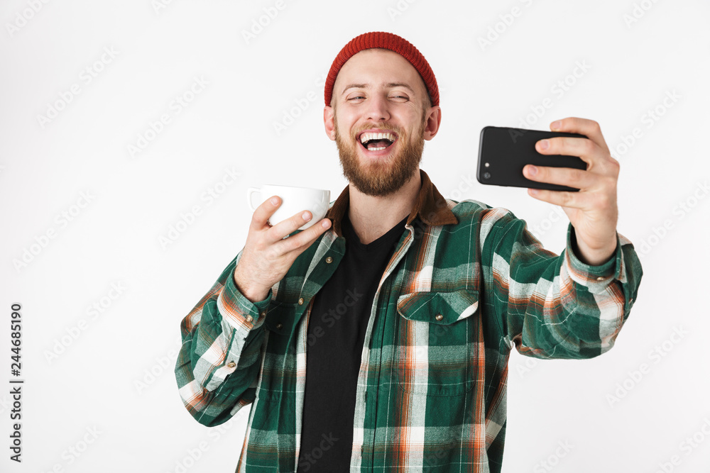 Naklejka premium Portrait of handsome man wearing plaid shirt holding credit card and cell phone, while standing isolated over white background