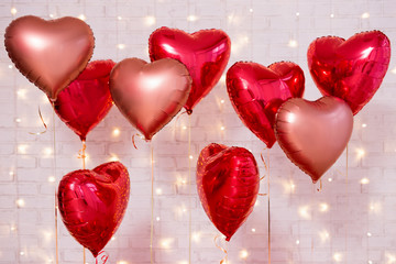Valentine's day background - group of red heart shaped balloons over brick wall