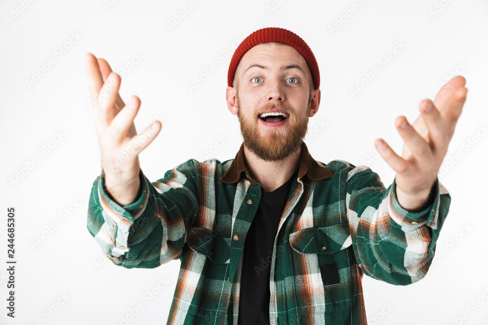 Photo of excited bearded guy wearing hat and plaid shirt gesturing, while standing isolated over white background Photo of excited bearded guy wearing hat and plaid shirt gesturing, while standing isolated over white background