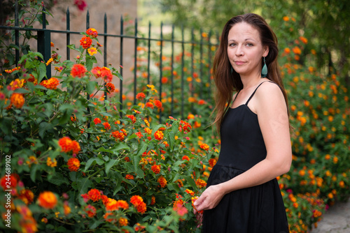 Young attractive woman in black dress posing with flowers