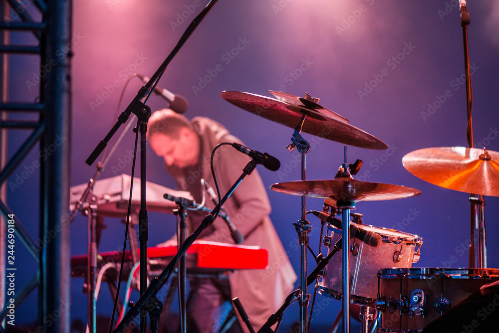 Artist playing on keyboard synthesizer piano keys, man playing drums on  stage during music festival in summer. Band performing their songs. Live  concert of electronic music at night. Colorful lights Stock Photo