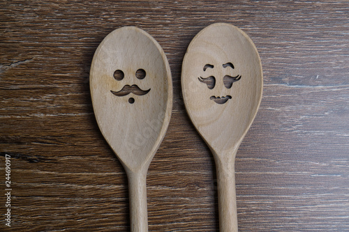 Wooden spoon with funny faces, woman and man, on wooden background