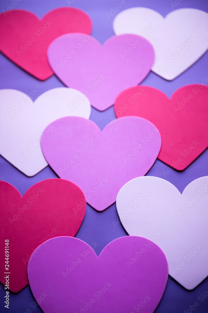 Simple Valentine's Day background of layered love hearts with copy space in shades of red, purple, and pink