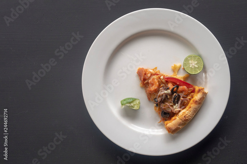 Seafood pizza slice on white plate on dark background