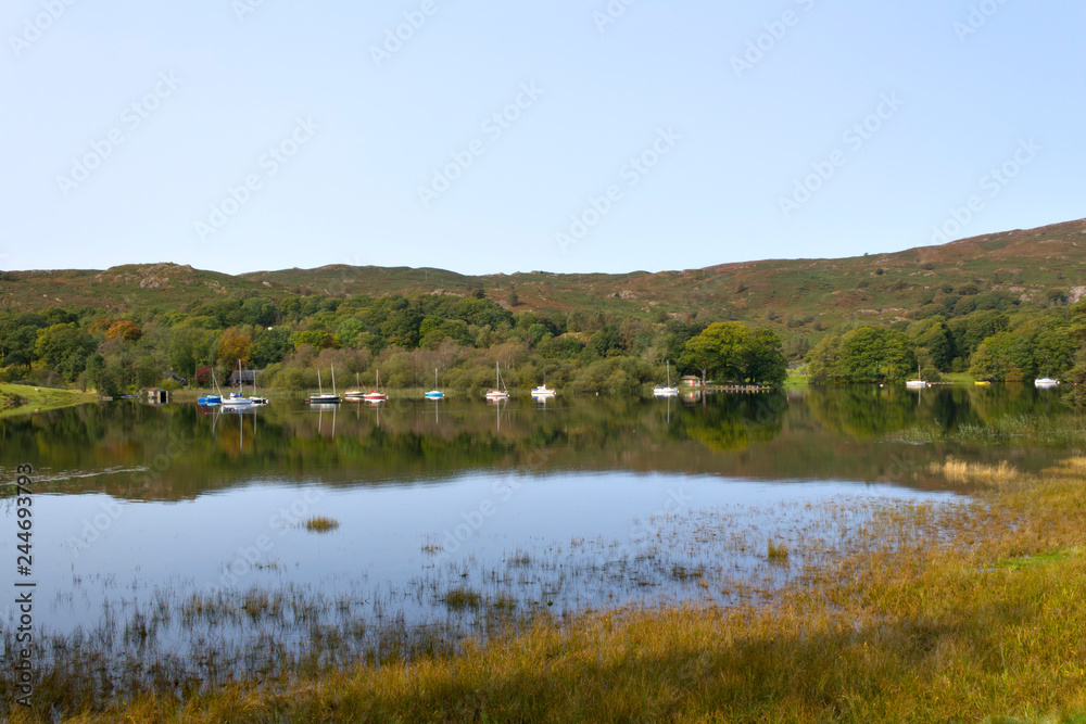 Boats moored at the southern end of Coniston Water on a tranquil early autumn morning in the Lake District, Cumbria, UK Boats moored at the southern end of Coniston Water on a tranquil early autumn morning in the Lake District, Cumbria, UK