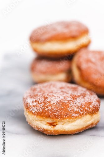 Traditional German or Austrian fried donuts with no hole, so called Krapfen, Berliner or Pfannkuchen with cinnamon sugar and filled with rose hip, raspberry or strawberry jam, party or carnival food © Corinna Haselmayer