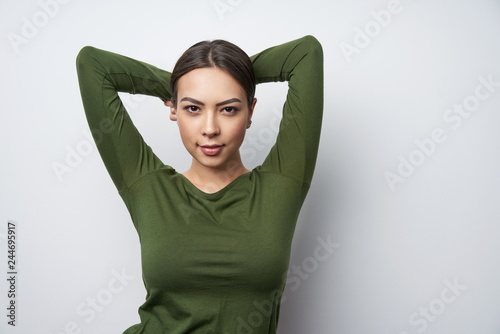 Smiling brunette female in green shirt standing with hands over head © paffy